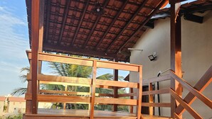 A wooden staircase with a view of palm trees and a building in the background. - Cottage 150 meters from the sea, located on Coqueiro beach in Luis Correia. (Coqueiro Luís Correia)