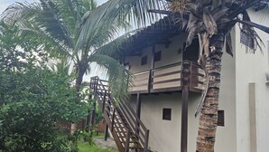 A two-story building with a wooden staircase leading to a balcony. - Cottage 150 meters from the sea, located on Coqueiro beach in Luis Correia. (Coqueiro Luís Correia)