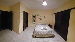 A bedroom with a bed, a bench, a wardrobe, and a mirror. - Cottage 150 meters from the sea, located on Coqueiro beach in Luis Correia. (Coqueiro Luís Correia)