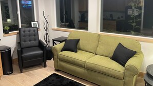 A living room with a green sofa, a black armchair, and a black rug. - Wisc Dells Romantic Getaway for two (Baraboo)