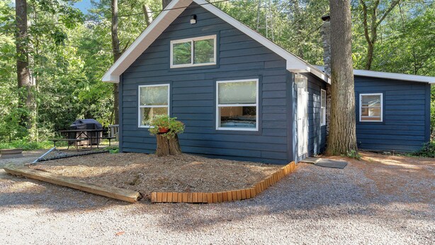 A blue cabin with a sloped roof, surrounded by trees. - Wisc Dells Romantic Getaway for two (Baraboo)