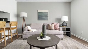 Ett modernt vardagsrum med en grå soffa, ett runt soffbord och en golvlampa.