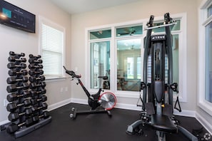 A home gym with a stationary bike, elliptical, and a bench press.