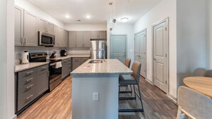 A modern kitchen with granite countertops, stainless steel appliances, and a central island. - Landing Myrtle Beach (Socastee)