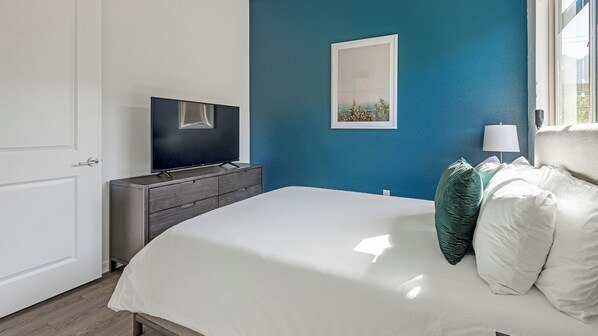 Une chambre à coucher avec un lit, une commode, un téléviseur et une fenêtre.