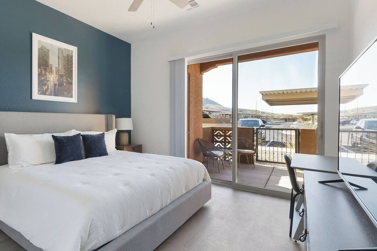 Une chambre d’hôtel moderne dotée d’un grand lit, d’un bureau et d’un balcon donnant sur le parking.