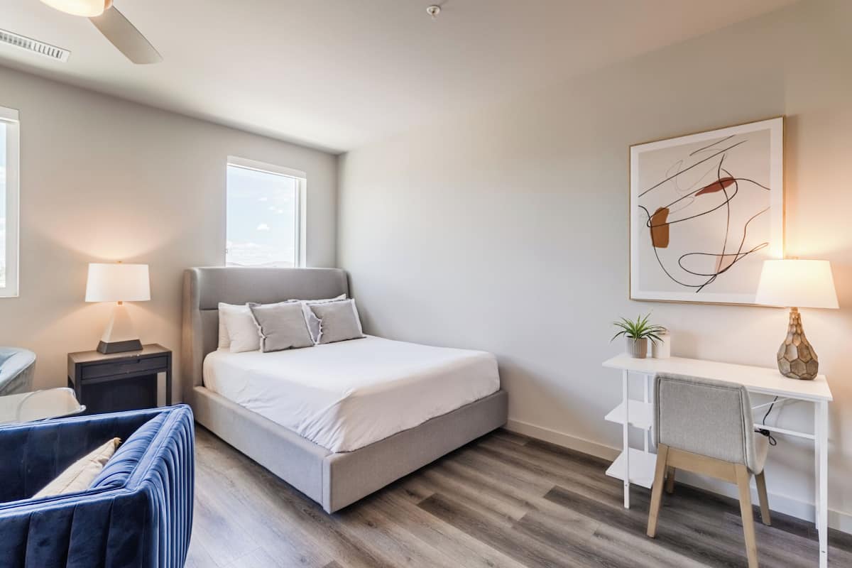 A modern bedroom with a bed, bedside tables, a desk, and a chair.