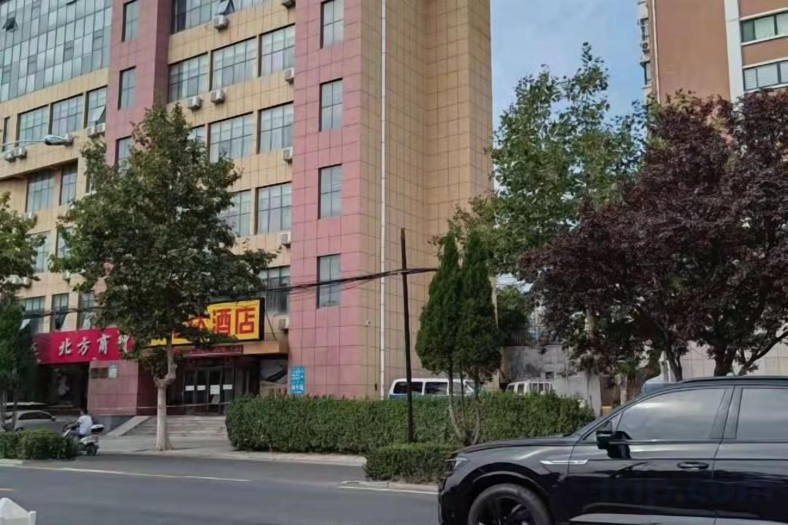 A multi-story building with a red sign indicating a hotel.