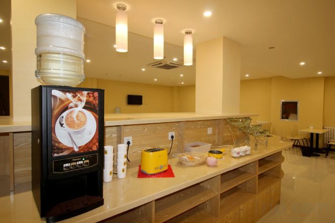 A hotel reception area with a coffee machine, water dispenser, and various amenities on the counter.