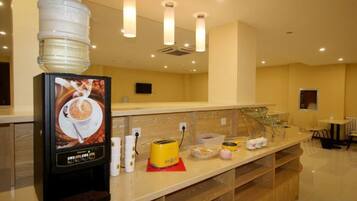 A hotel reception area with a coffee machine, water dispenser, and various amenities on the counter.