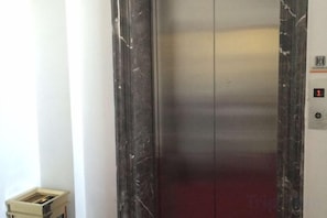 An elevator with a marble finish and a digital display showing the number 1. - Cinda Hotel (Zhaoyuan)