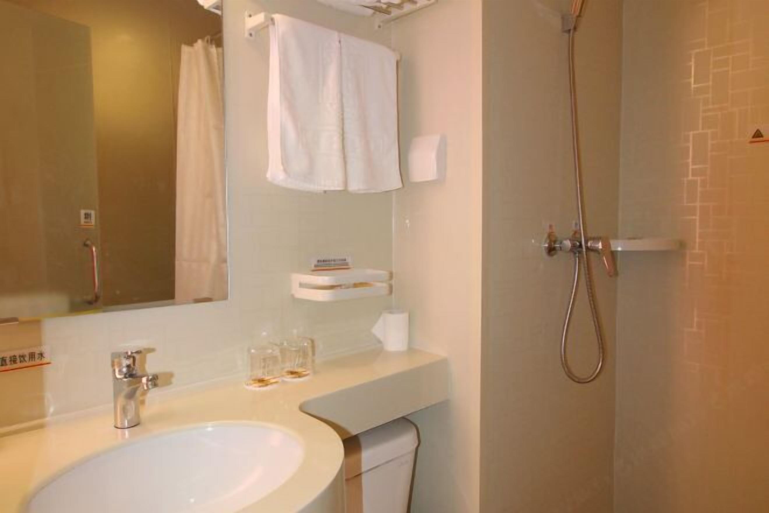 A bathroom with a sink, mirror, towel rack, and shower.