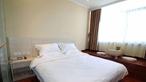 A hotel room with a large bed, a bedside table, a chair, and a window with curtains. - Cinda Hotel (Zhaoyuan)