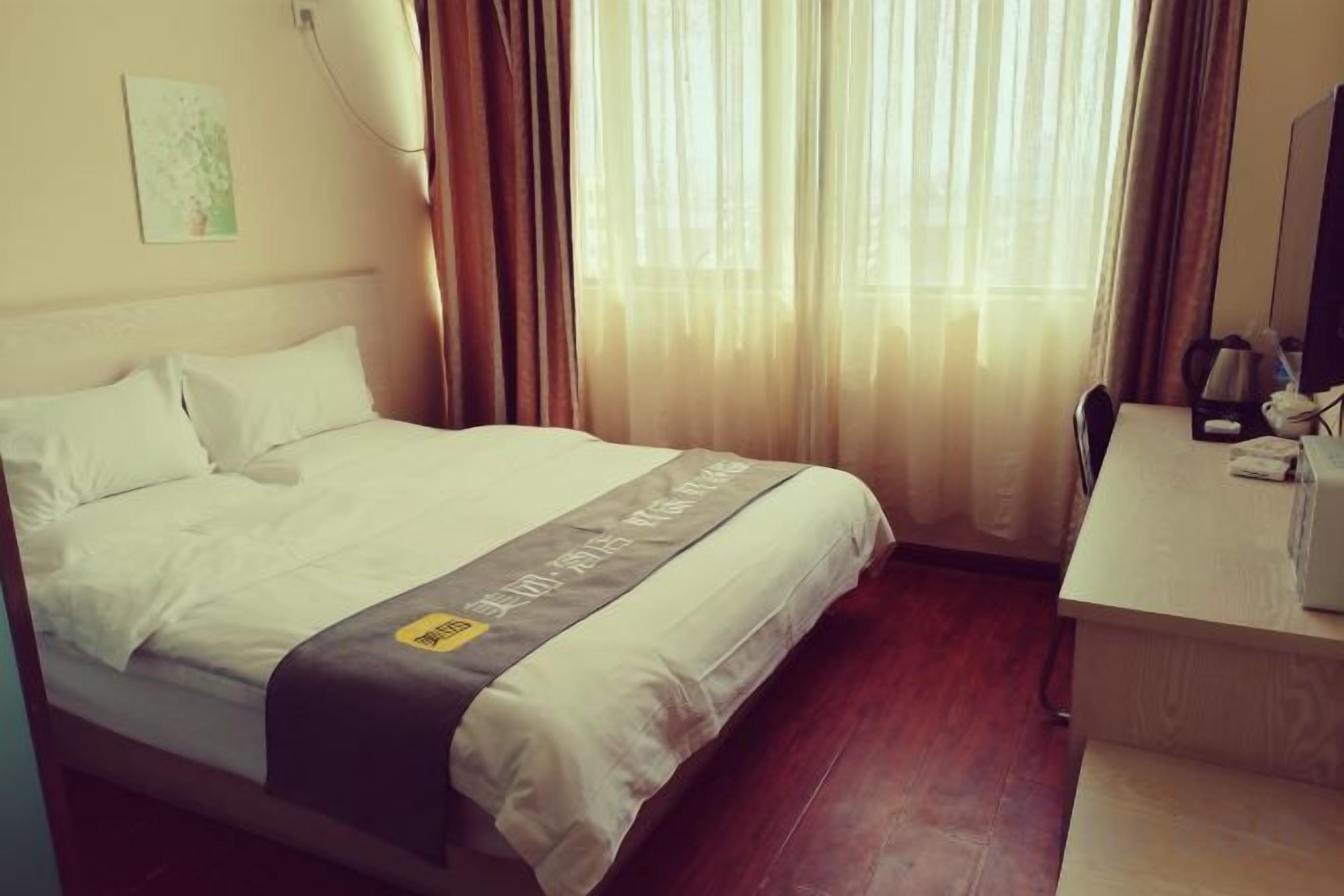 Een hotelkamer met een bed, een bureau en een raam met gordijnen.