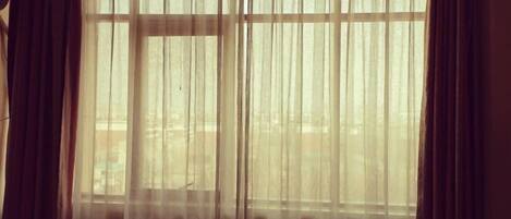 A room with a large window covered by sheer curtains, allowing natural light to enter.