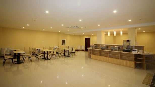 A spacious hotel lobby with multiple tables and chairs, a reception desk, and a clean, polished floor. - Cinda Hotel (Zhaoyuan)