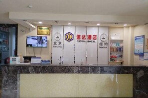 A hotel reception desk with a digital screen, a clock, and a sign indicating the hotel's name and location. - Cinda Hotel (Zhaoyuan)