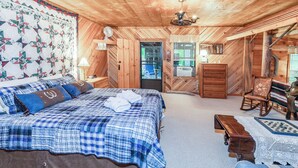 A wooden cabin bedroom with a bed, dresser, and a rocking chair.