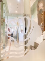 Un interior moderno con un separador de vidrio y una escultura decorativa de metal blanco.