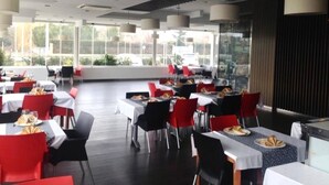Un restaurant avec des tables et des chaises, de grandes fenêtres et une vue sur l’extérieur.