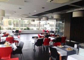 Un restaurante con mesas y sillas, ventanas amplias y vistas al exterior.