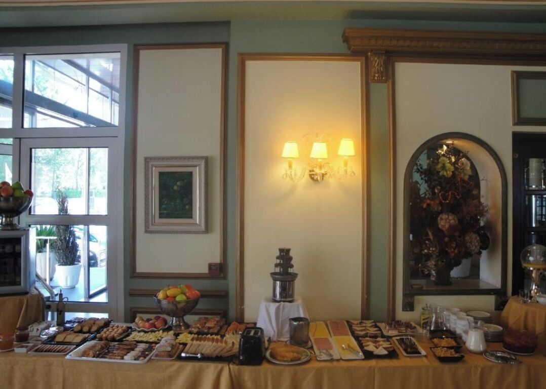 A buffet table with various food items, a wall-mounted lamp, and framed artwork.