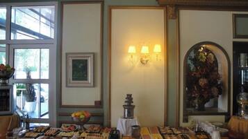 A buffet table with various food items, a wall-mounted lamp, and framed artwork.