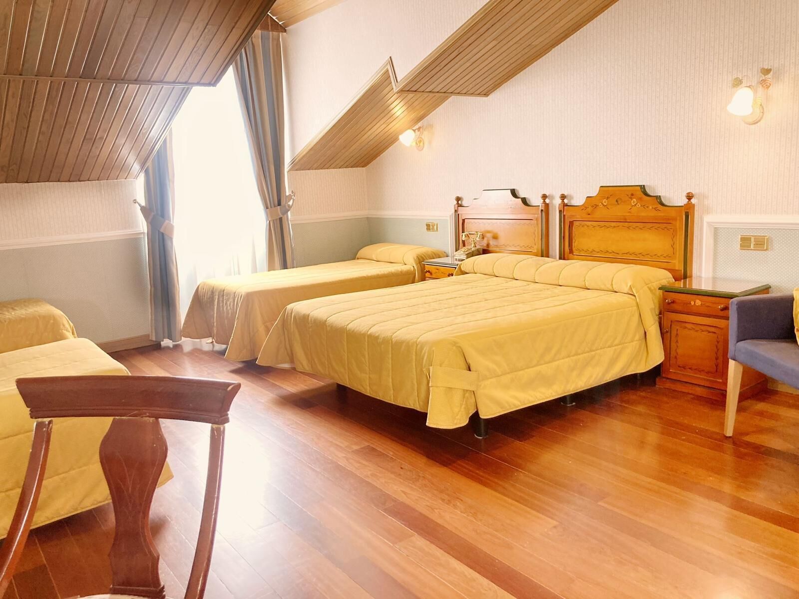 A hotel room with two beds, wooden furniture, and a view of the outdoors.