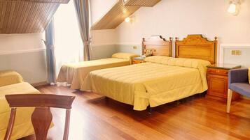 A hotel room with two beds, wooden furniture, and a view of the outdoors.
