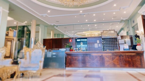 Un hall d’hôtel agrémenté d’un magnifique lustre, d’un comptoir d’accueil et de meubles richement décorés.