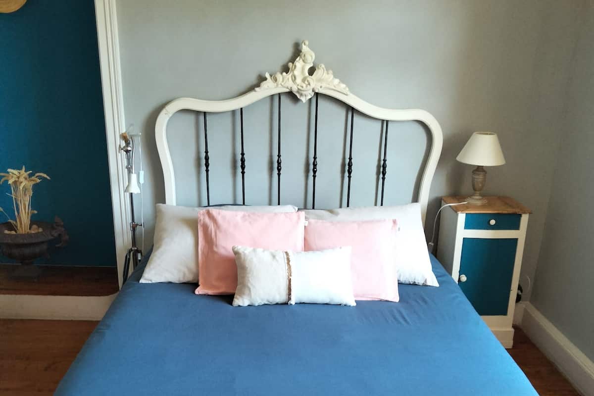A bed with a white headboard, blue bedding, and two bedside tables with lamps.