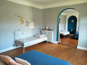 A room with a metal bed frame, a blue mattress, a radiator, and a wooden floor. - Les moulins de Clan (Jaunay-Marigny)
