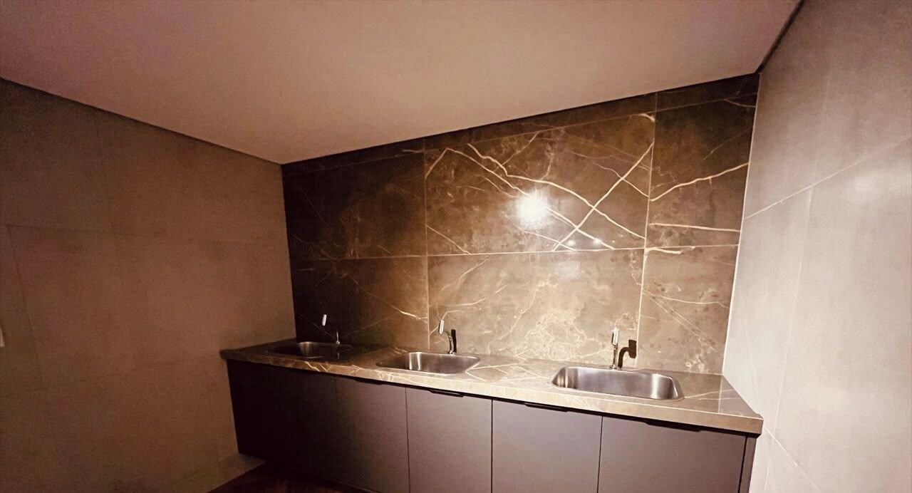 Une salle de bain moderne avec deux vasques, un pare-feu en marbre et des meubles aux tons foncés.