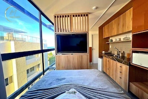 Eine moderne Küche mit großem Fernseher, Holzschränken und Blick auf die Stadt.
