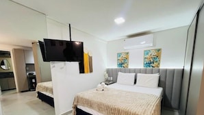 Une chambre d’hôtel avec un lit, une télévision, une table de chevet et des œuvres d’art accrochées au mur.
