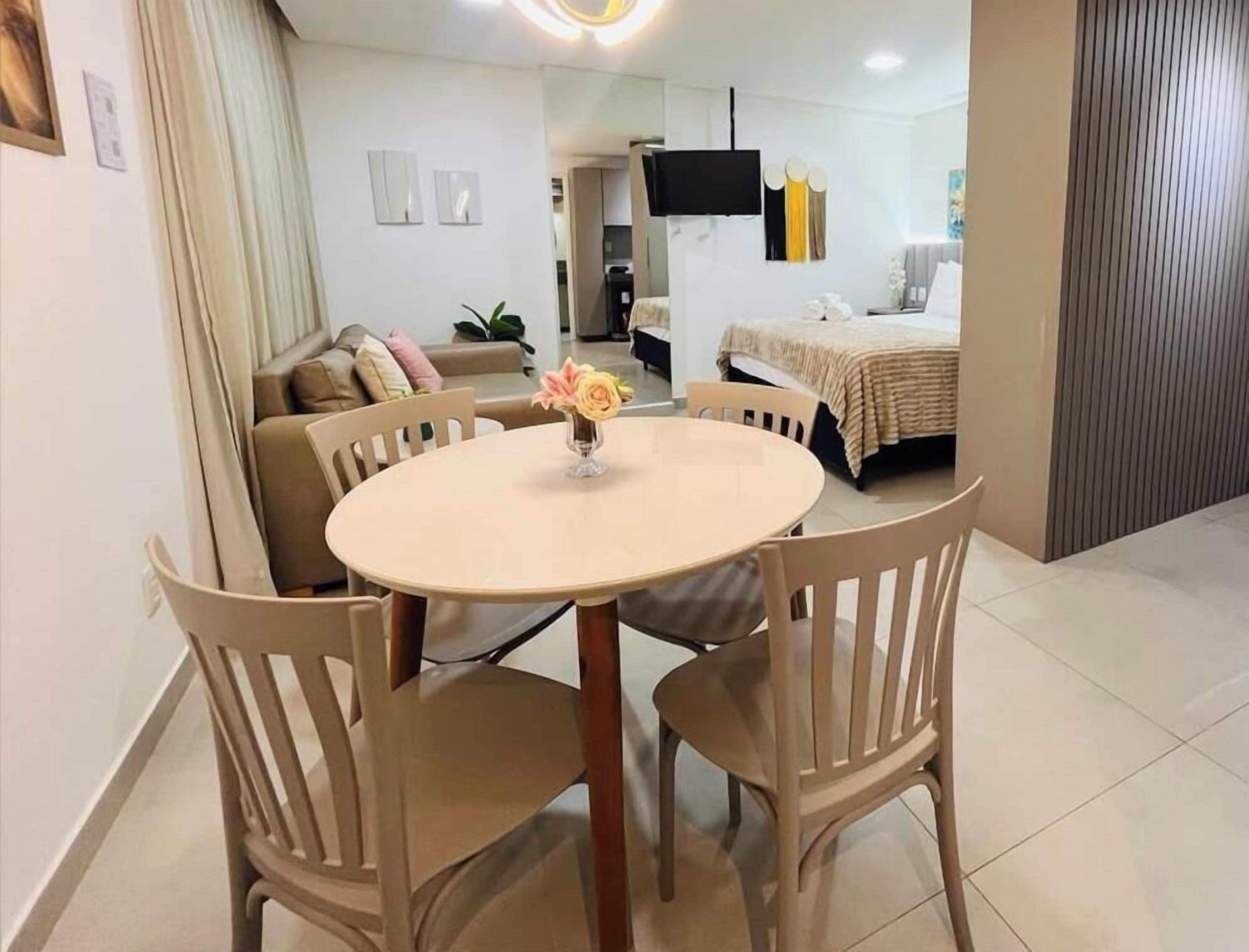A modern living room with a round table, two chairs, a sofa, and a television mounted on the wall.