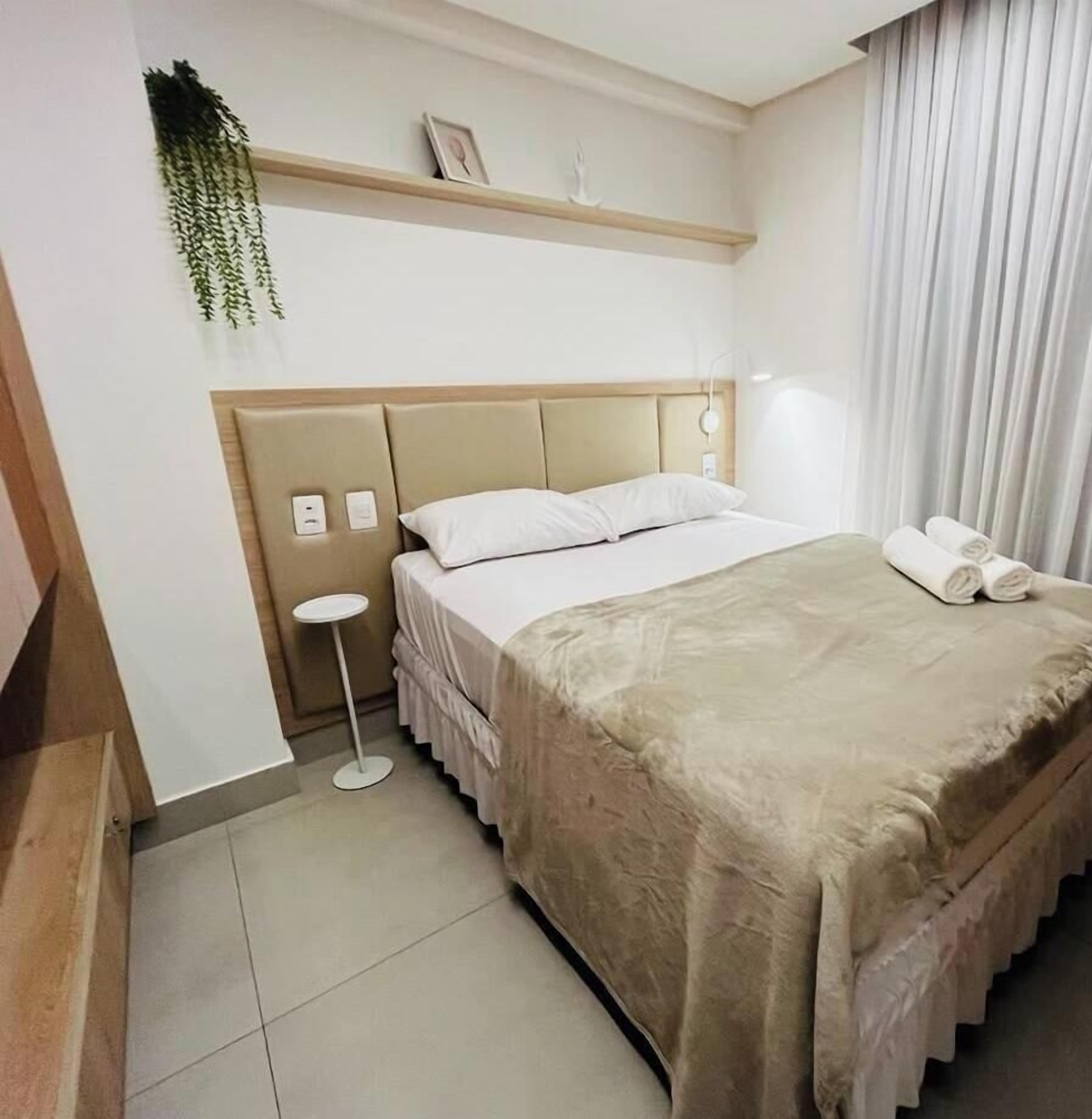 Een hotelkamer met een bed, nachtkastje en een hangplant.