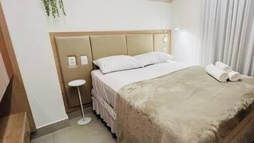 Habitació d'hotel amb llit, taula de nit i una planta penjant.