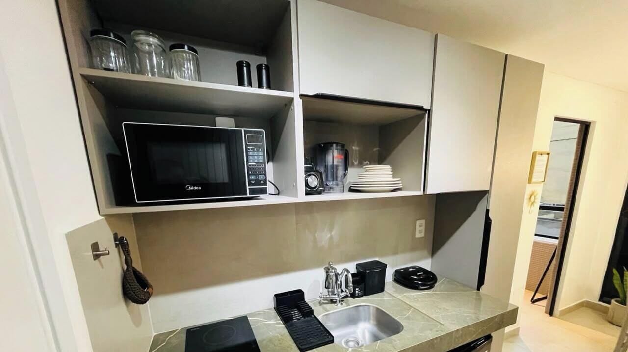 Cocina compacta con microondas, cafetera y lavabo.