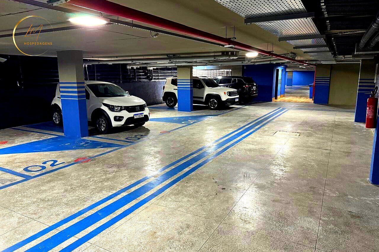 A parking garage with multiple parking spaces, blue lines, and pillars.