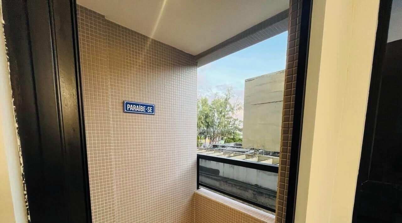 Une pièce avec un mur recouvert de carreaux, une fenêtre donnant sur l’extérieur et un panneau indiquant « PRAIA-SE ».
