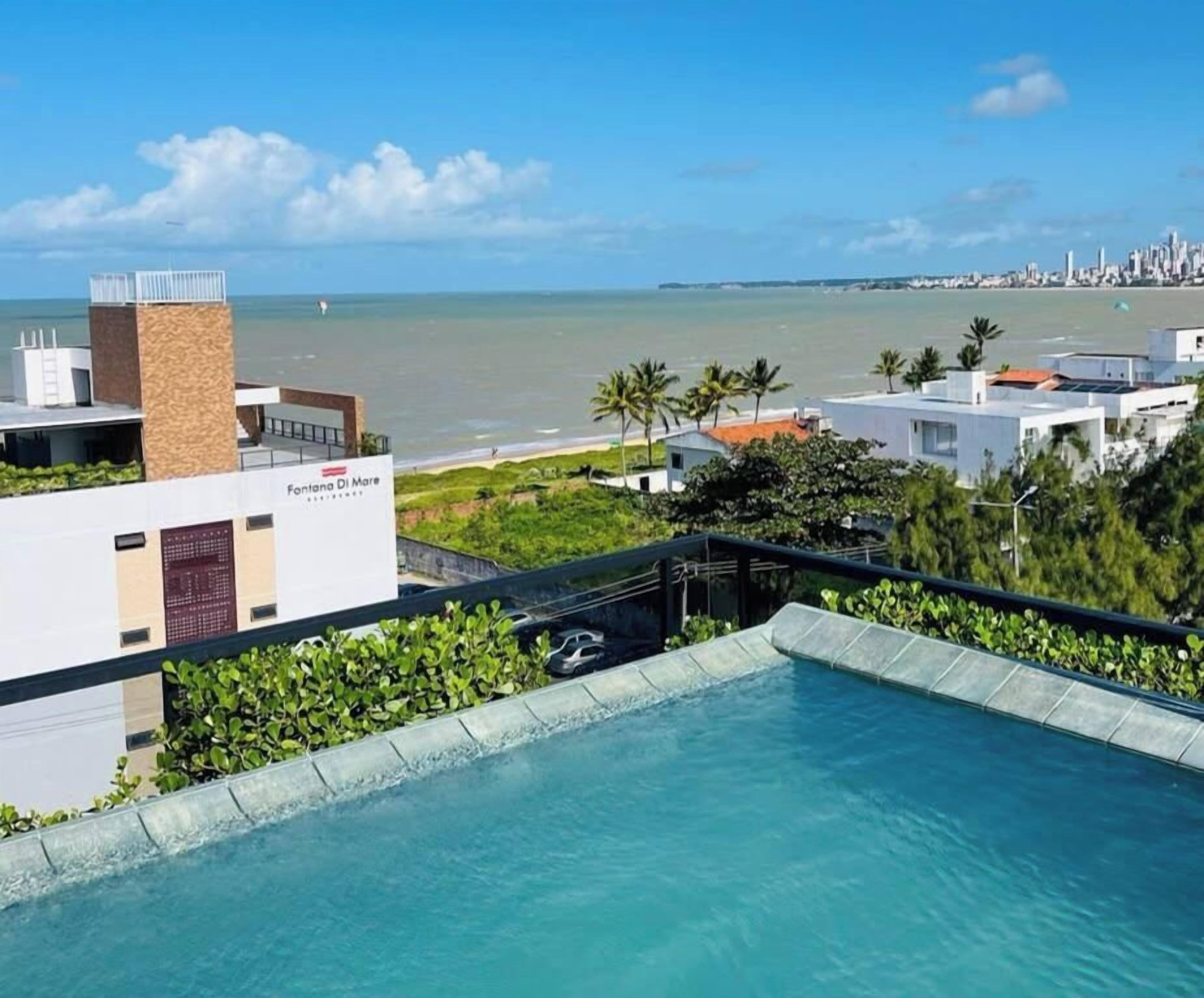 A pool with a view of the beach and city skyline.
