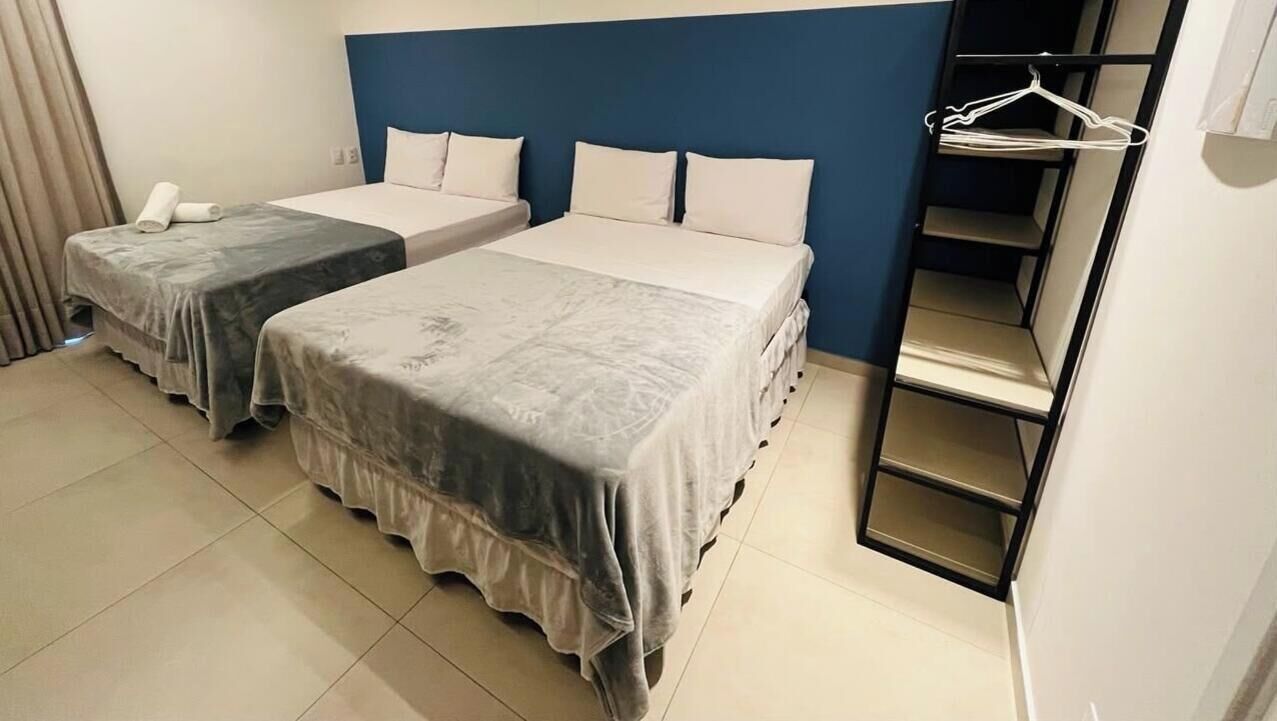 Habitación de hotel con dos camas, un armario y una percha.