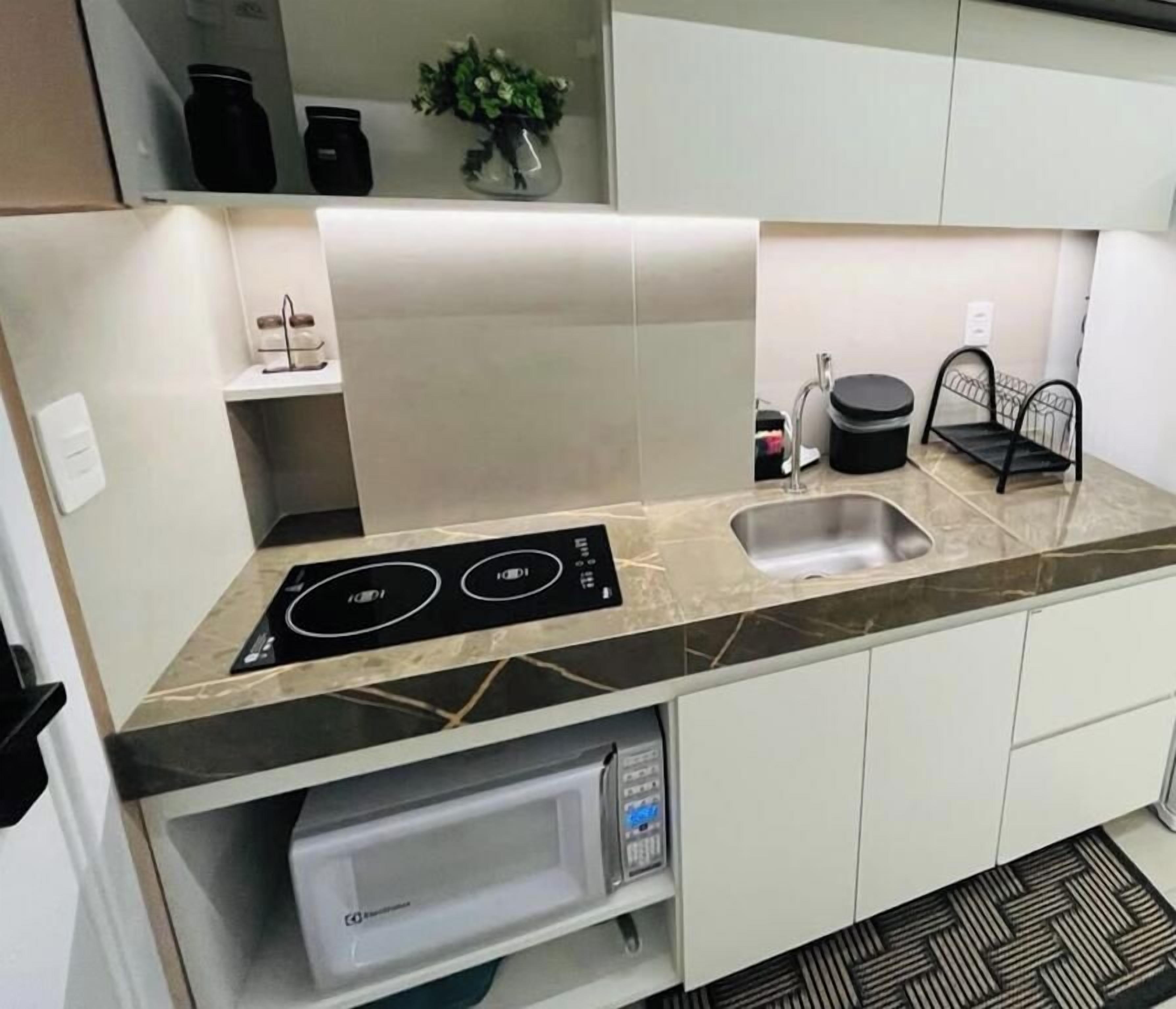 Una cucina moderna con piano cottura integrato, lavello e mobili bianchi.