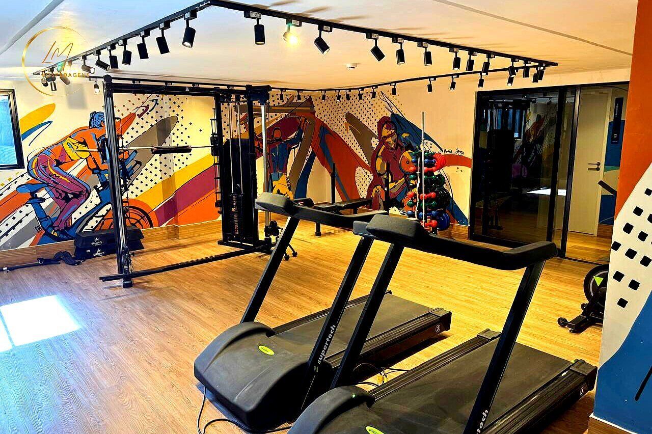 Un gimnasio con cintas de correr, una pared con arte abstracto y suelo de madera.
