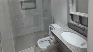 Ein modernes Badezimmer mit einer gläsernen Dusche, einer Toilette und einem Waschbecken mit Granitplatte.