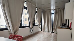 A room with a dining table, red chair, and a kitchenette area with a coffee machine. - CconfortHotels eXtramurale Apartment (Bari)