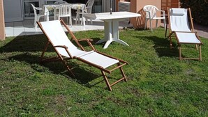 An outdoor patio with a table and chairs, a white umbrella, and a grassy area. - T1 with exceptional sea view-HAMEAU CAP ESTEREL- VILLAGE VACANCES -AGAY (Saint-Raphaël)