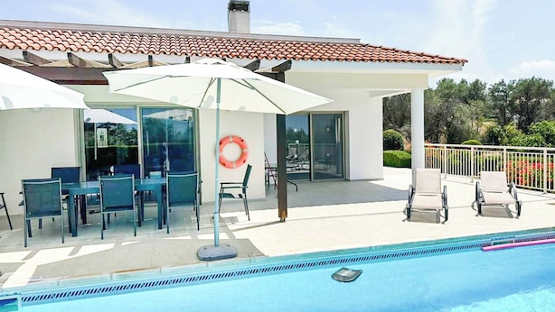 Un espace aménagé au bord de la piscine, avec un patio couvert, des sièges d’extérieur et une bouée de sauvetage.