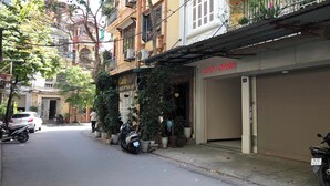 Vista de la calle con un café llamado 'COZY OASIS' y una tienda cerrada con una persiana.